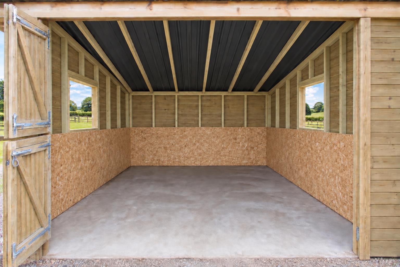 Stable interior with OSB kick boards, sloping rafters and bare concrete base